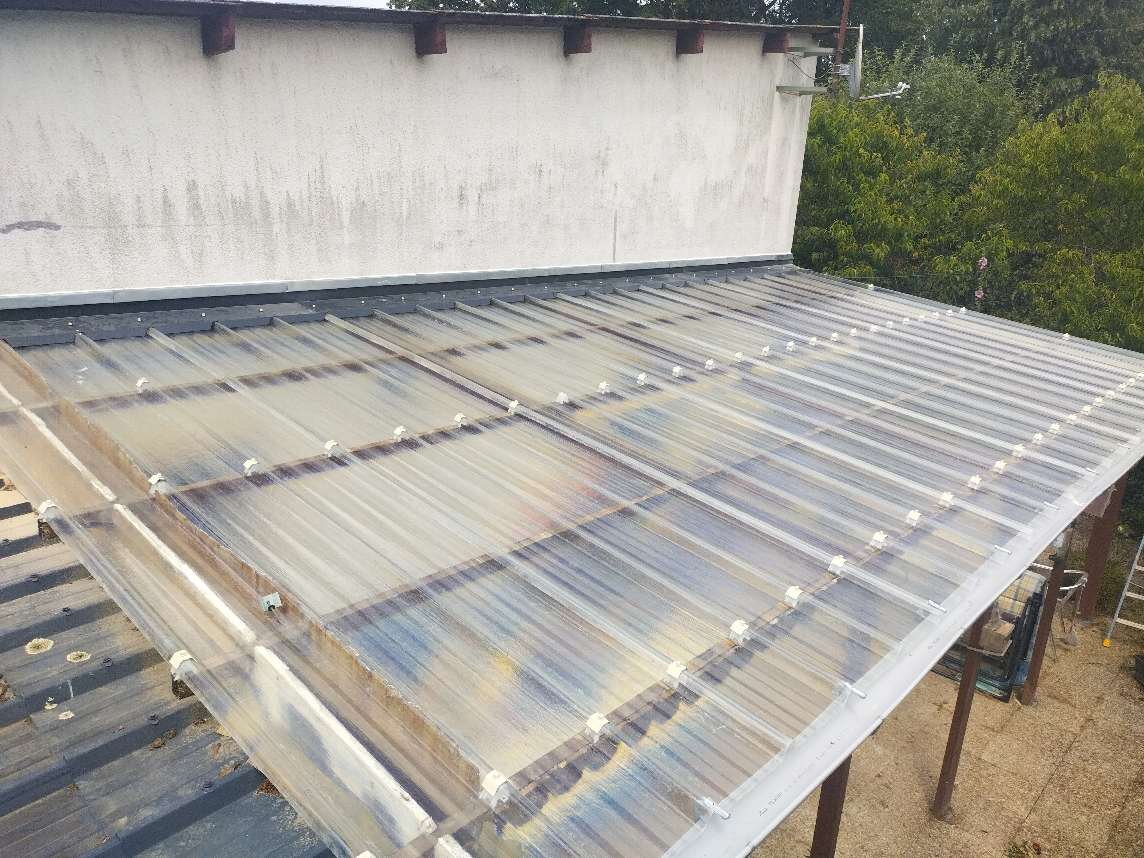 Couverture en tôle ondulée transparente sur une véranda, installation réalisée par Couverture Delalande.