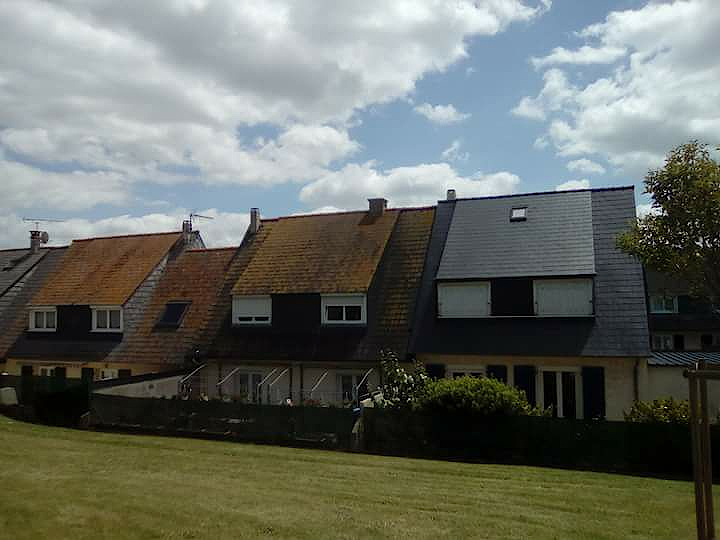 Comparaison entre une toiture avant et après démoussage, montrant l'efficacité du nettoyage effectué par Couverture Delalande.